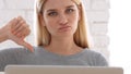 Thumbs Down by Frustrated Woman Sitting in Office