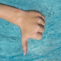 thumbs down sign of young man, teenager with blue water as background