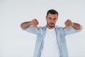 Thumbs down. Young handsome man standing indoors against white background Royalty Free Stock Photo