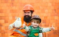 Thumbs up against the background of a brick wall. Construction concept. Happy family together. Happy father and son in