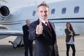 Thumbs up business team in front of corporate private jet Royalty Free Stock Photo