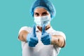 Thumbs up. Doctor wearing medical uniform showing thumbs up at camera. Isolated on a blue background