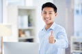 Thumbs up, sign and finger being shown by a happy, smiling and pleased businessman while standing in an office at work Royalty Free Stock Photo