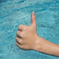 thumbs up sign of young man, teenager with blue water as background