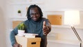 Thumbs up. Unrecognizable man with carboard box over the head package books and piggy bank relocating in new property Royalty Free Stock Photo