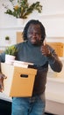 Thumbs up. Unrecognizable man with carboard box over the head package books and piggy bank relocating in new property Royalty Free Stock Photo