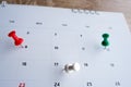 Thumbtack a date on calendar on the table with wooden background, concept for important date, meeting reminder, planning for