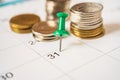 thumbtack marked 31st day, end of month, in soft focus and blurred stack of coins on white calendar Royalty Free Stock Photo
