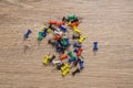 Thumbtacks of different bright colors are scattered randomly on a wooden background Royalty Free Stock Photo