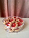 Thumprint cookies in a jar on a wooden table with curtains background