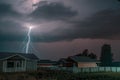 Thunderbolt over the house in the village and dark stormy sky on the background Royalty Free Stock Photo