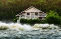 Thundering waters of a river in front of a fragile wooden house, which defies the devastating storm at the edge of a forest, made