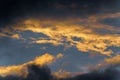 Thunderstorm clouds illuminated by disappearing rays at sunset, thunderclouds floating across sunny blue sky to change Royalty Free Stock Photo