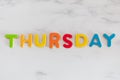 Thursday word written with colorful letters on white marble stone background Royalty Free Stock Photo