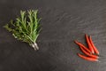 Thyme, rosemary bundles and chili peppers on black stone surface background Royalty Free Stock Photo