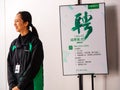 TIANHE, GUANGZHOU CITY, CHINA - 7 MAR 2019 - Smiling Asian Chinese Oppo employee stands next to an staff recruitment poster