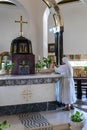 A monk nun in white robes puts a candle on the altar in the central hall of the Beatitude Monastery located on the mountain on the