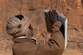 Young local man from Chad is making a photo by using tablet. In the background rock formations of Tibesti