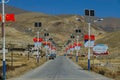 Asphalt avenue with solar powered lamps leads through rugged landscape in Tibet.