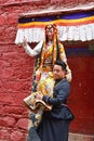 Tibet, Lhasa, China, June, 02, 2018. Tibetan woman in a national costume sitting on the shoulder of a man near the wall of ancient