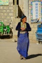 CLOSE UP: Tibetan woman crosses the empty street and looks around the village Royalty Free Stock Photo