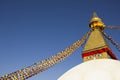 A Tibetan Buddhist Stupa Boudhanath with eyes and multicolored prayer flags against a clean blue sky Royalty Free Stock Photo