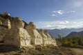 A Tibetan Buddhist white temples of stupa on a stony hillside against the backdrop of a mountain valley under a blue sky and white Royalty Free Stock Photo