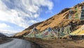 Tibetan landscape in China with prayer flags on foreground and a road on left side Royalty Free Stock Photo