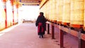 Tibetan monk and nun walking and spinning the prayer wheels in Yarchen Gar Monastery