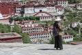 Tibetan pilgrim woman in Drepung monastery wearing traditional clothes and a wide hat for sun protection near Lhasa