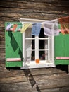 Tibetan prayer flags on green shutters and white window on typical and traditional austrian alpine wooden house - Salzkammergut