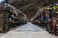Tibetan prayer flags swaddled with bridge over frozen river with Black mountain with snow on the top is background at Thangu. Royalty Free Stock Photo