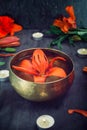 Tibetan singing bowl with floating lily inside. Burning candles, lily flowers and petals on the black wooden background. Meditatio Royalty Free Stock Photo