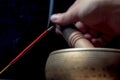 Tibetan singing bowl and incense stick. Man`s hand over the bowl Royalty Free Stock Photo