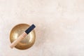 Tibetan singing bowl with sticks used during mantra meditations on beige stone background, top view, copy space Royalty Free Stock Photo