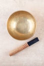 Tibetan singing bowl with sticks used during mantra meditations on beige stone background, top view, flat lay Royalty Free Stock Photo