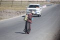 Tibetan women cross the road with their heads down, carrying water tanks full of water on their backs