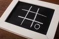 Tic tac toe game on blackboard with chalk grid and naught Royalty Free Stock Photo