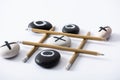 Tic tac toe game with grid made of pencils and pebbles marked with naughts and crosses Royalty Free Stock Photo