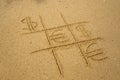 Tic-tac-toe game with playing euro and dollar symbols on sand. Royalty Free Stock Photo