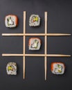 Tic tac toe game with sushi on dark black background, creative concept sushi rolls. Banner, playing tic tac toe game