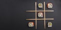 Tic tac toe game with sushi on dark black background, creative concept sushi rolls. Banner, playing tic tac toe game