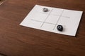 Tic tac toe game on white paper with pebbles marked with naught and cross Royalty Free Stock Photo