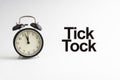 TICK TOCK inscription written and alarm clock on white background