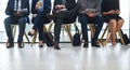 Tick tock...the time is ticking. a group of unrecognizable businesspeople sitting in line for an interview in a modern Royalty Free Stock Photo