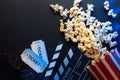 Ticket, popcorn, filmstrip and clapper, movies and entertainment concept on black background with blue neon light Royalty Free Stock Photo
