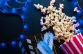 Ticket, popcorn, filmstrip and clapper, movies and entertainment concept on black background with blue neon light Royalty Free Stock Photo