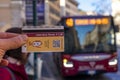 ticket or transport ticket for city buses held in hand with blurred bus background, Rome, Italy.