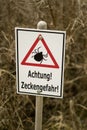 Ticks warning sign `Achtung! Zeckengefahr!` in Germany. Translation: Attention! Beware of Ticks! Royalty Free Stock Photo