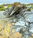 Tidal rock pool surrounded by smooth rocks and seaweed,Dollar Cove,Gunwalloe, Helston,Cornwall,England,UK